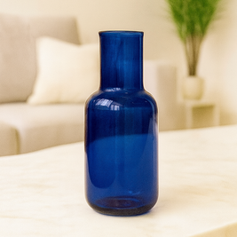 Blue glass bottle on a table with a blurred indoor background