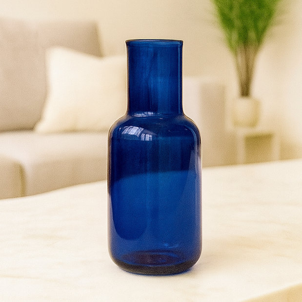 Blue glass bottle on a table with a blurred indoor background