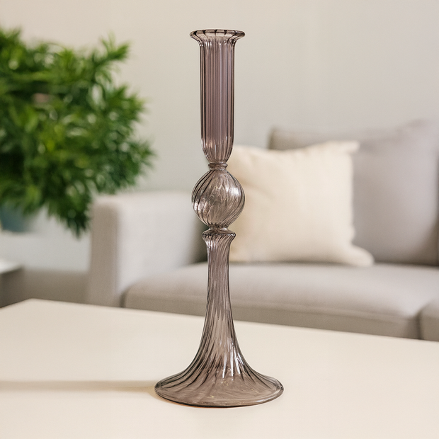 Decorative glass candlestick on a table with a blurred background of a living room.