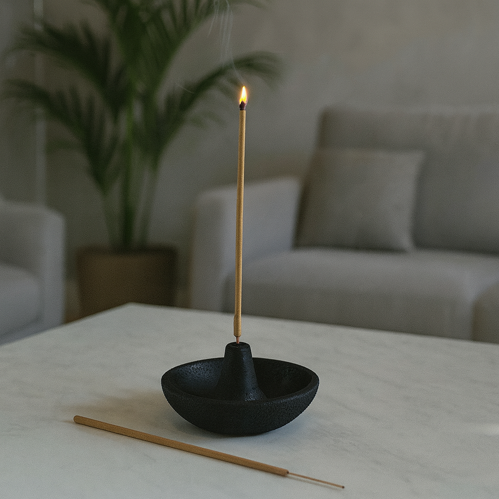 Incense stick burning in a black holder on a table with a blurred background