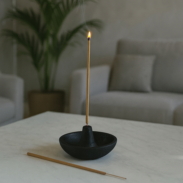 Incense stick burning in a black holder on a table with a blurred background