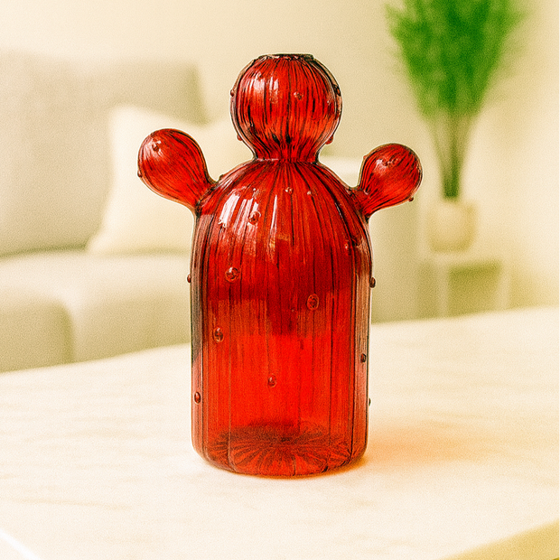 Red glass cactus-shaped object on a white surface with a blurred background