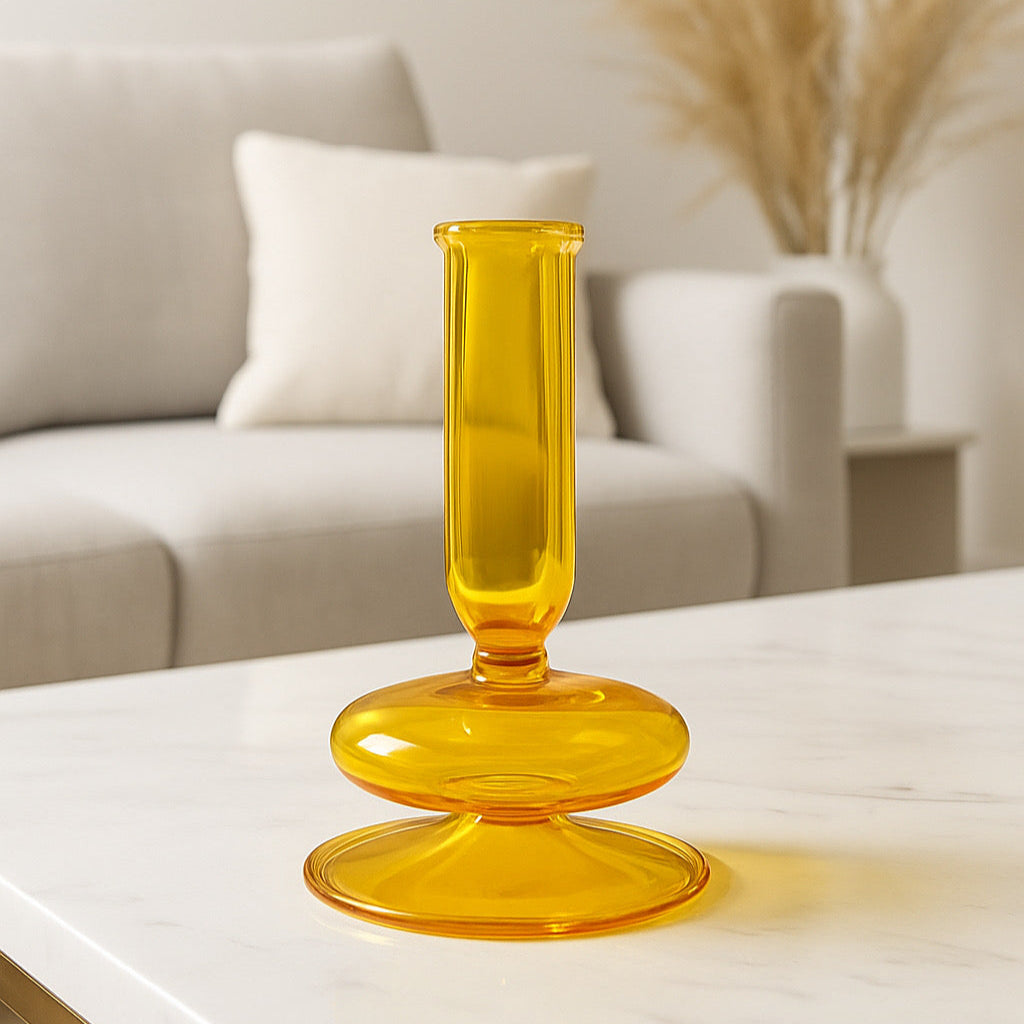 Yellow glass candle holder on a white surface with a blurred background