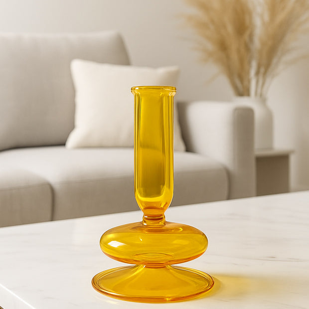Yellow glass candle holder on a white surface with a blurred background